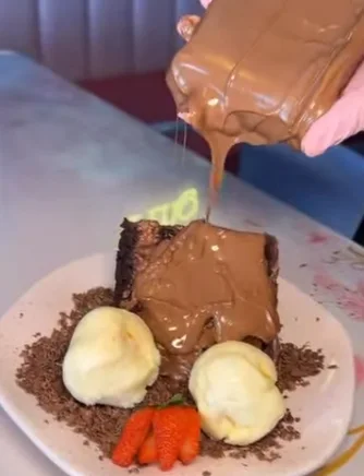 Fatia de bolo de chocolate coberta com chocolate derretido, sorvete e morangos